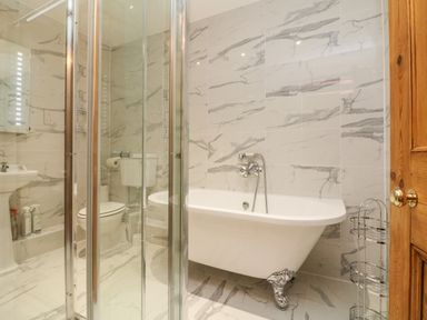 A bathroom with a freestanding bathtub pedestal sink toilet and glass shower at The Shippen in Gooseham near Kilkhampton