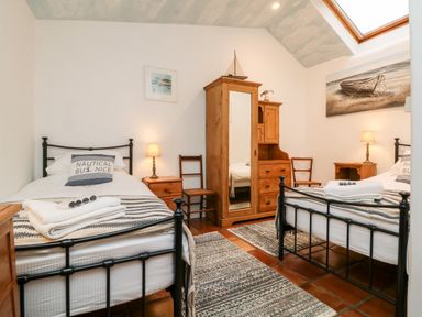 A bedroom with two single beds wooden furniture rugs and a skylight at The Shippen in Gooseham near Kilkhampton
