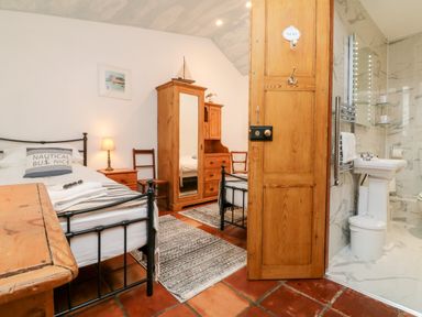 A bedroom with two single beds wooden furniture and an attached bathroom at The Shippen in Gooseham near Kilkhampton