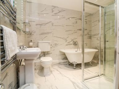 A bathroom with a pedestal sink a toilet a clawfoot bathtub and a glass shower enclosure at The Shippen in Gooseham near Kilkhampton