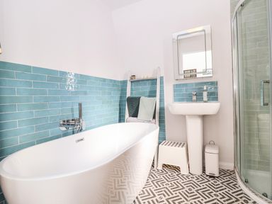 A bathroom with a bathtub sink shower and towel rack at Sea Mouse Cottage in Southwold