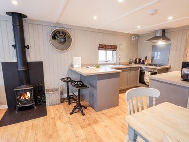 A kitchen with a wood-burning stove two bar stools and a dining table at Grouse Lodge in Seamer North Yorkshire