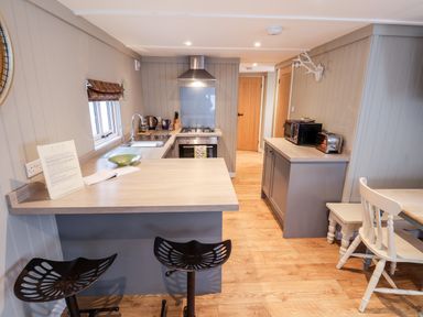 A kitchen with a breakfast bar stools oven microwave toaster and a dining table at Grouse Lodge in Seamer North Yorkshire