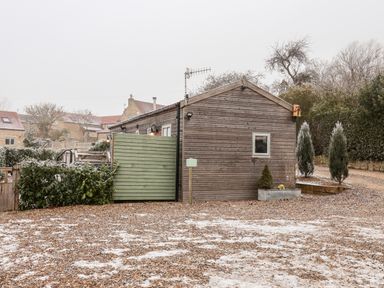 A wooden single-story building with a green gate and gravel ground at Grouse Lodge in Seamer North Yorkshire