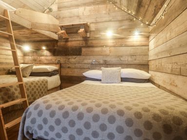 A bedroom with a double bed a wooden bunk bed a ladder and wall-mounted clothes hangers at Foxes Den in Seamer North Yorkshire