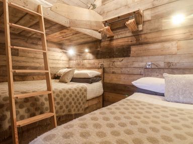 A bedroom with two beds a wooden ladder and clothes hangers on wooden walls at Foxes Den in Seamer North Yorkshire