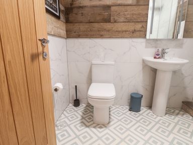 A bathroom with a toilet sink mirror and wooden and marble wall panels at Foxes Den in Seamer North Yorkshire