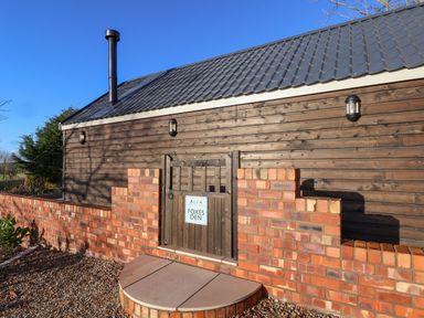 Exterior view of a wooden building with a brick wall and a small gate with a sign that says Foxes Den in Seamer North Yorkshire