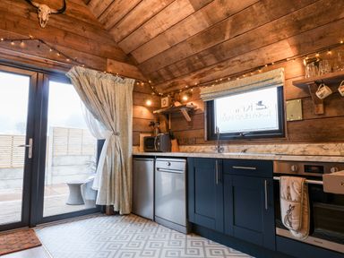A kitchen with blue cabinets white marble countertop a dishwasher an oven a microwave and a glass door at Sunset Retreat in Seamer North Yorkshire