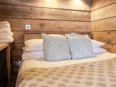 A bed with pillows and folded towels on a wooden side table in a room with wood-paneled walls at Sunset Retreat in Seamer North Yorkshire