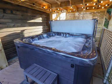 A covered outdoor hot tub with bubbling water and wooden steps at Sunset Retreat in Seamer North Yorkshire