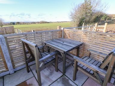 A wooden table with four wooden chairs on a patio overlooking a field at Sunset Retreat in Seamer North Yorkshire