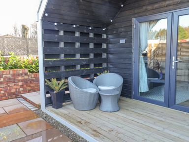 A small outdoor seating area with two grey chairs and a table on wooden decking at Sunset Retreat in Seamer North Yorkshire