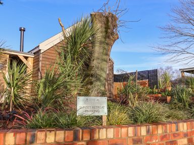 A garden area with plants and a tree stump next to a wooden shed and a parking sign at Sunset Retreat in Seamer North Yorkshire