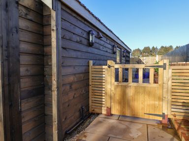 An outdoor area with a wooden gate next to a dark wooden building at Sunset Retreat in Seamer North Yorkshire