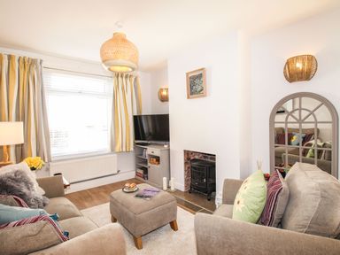 A living room with two sofas a cushioned ottoman a television and a fireplace at Quarrier's Rest in Swanage