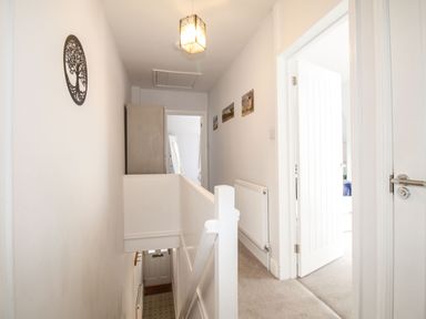 A hallway with white walls a stair railing a radiator and open doors at Quarrier's Rest in Swanage