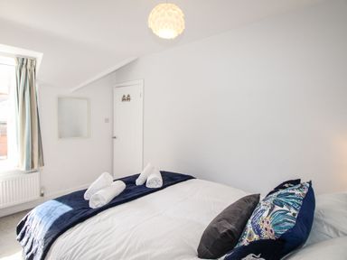 A bedroom with a bed with pillows and rolled towels near a window at Quarrier's Rest in Swanage