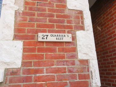 A brick wall with a white sign showing number 27 and the name Quarrier's Rest