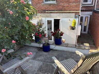 A garden with flowering plants and wooden chairs at Quarrier's Rest in Swanage