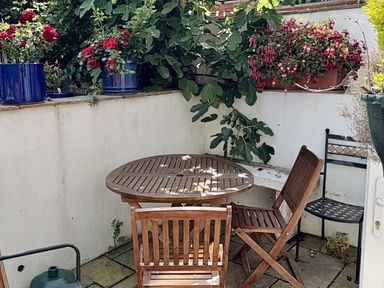 A garden with a table and chairs surrounded by flower pots at Quarrier's Rest in Swanage