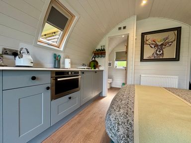 A compact kitchen and bedroom area with a bed and a painting of a deer at Oh Deer in Ashbourne