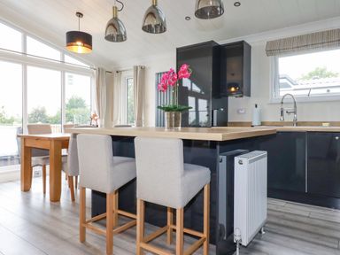 A kitchen with a wooden countertop island and two gray bar stools at Mordros Lodge in St Day