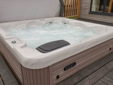 An outdoor hot tub with bubbling water on a wooden deck at Mordros Lodge in St Day