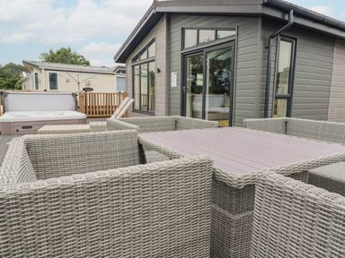 An outdoor seating area with wicker chairs and a table next to a grey building at Mordros Lodge in St Day