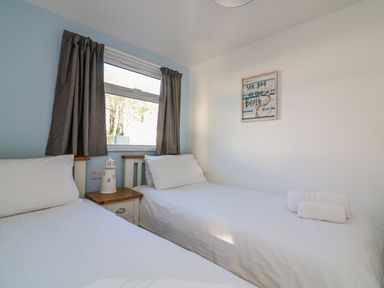 A bedroom with two single beds a nightstand and a window at Beachcomber in Norton Park near Dartmouth