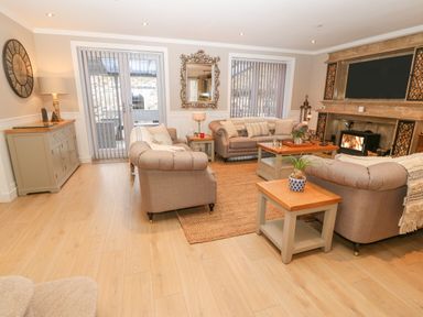 A living room with three sofas a coffee table a side table a cabinet a wall clock a fireplace and a mirror at Ty Bains in Llanberis