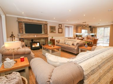 A living room with sofas a coffee table a fireplace and an open kitchen at Ty Bains in Llanberis
