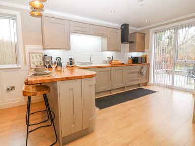 A kitchen with wooden countertops bar stools and cabinets at Ty Bains in Llanberis