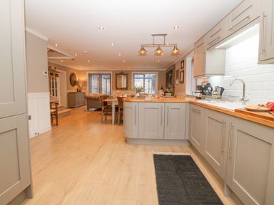 An open kitchen and dining area with wooden floors cabinets and a dining table at Ty Bains in Llanberis