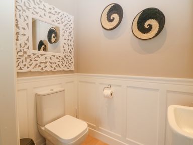 A bathroom with a toilet a decorative mirror and two round wall hangings at Ty Bains in Llanberis