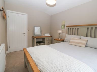 A bedroom with a double bed desk with mirror bedside table and door at Ty Bains in Llanberis