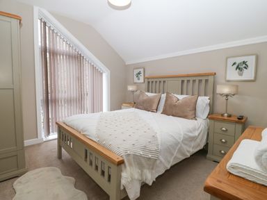 A bedroom with a bed a wardrobe bedside tables lamps and window blinds at Ty Bains in Llanberis