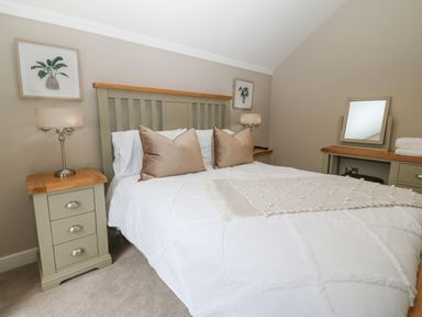 A bedroom with a bed between two nightstands with lamps and a dresser with a mirror at Ty Bains in Llanberis