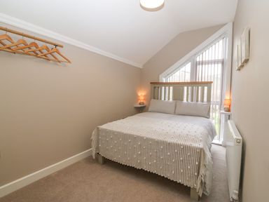 A bedroom with a double bed two wall lamps and wooden hangers on a rail at Ty Bains in Llanberis