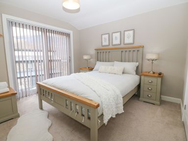 A bedroom with a bed between two nightstands and vertical blinds on the window at Ty Bains in Llanberis
