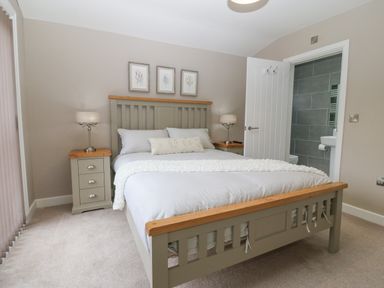 A bedroom with a bed and bedside tables with lamps and an open door leading to a bathroom at Ty Bains in Llanberis