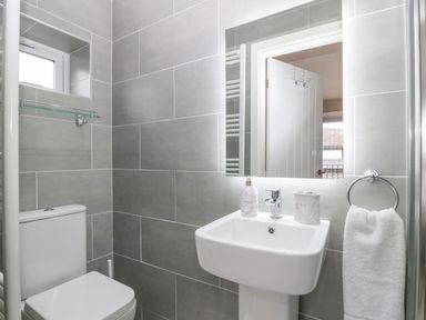 A bathroom with a toilet sink mirror towel ring and tiled walls at Ty Bains in Llanberis