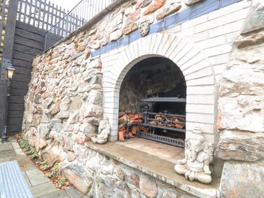An outdoor stone fireplace with wood and two elephant statues on the sides at Ty Bains in Llanberis