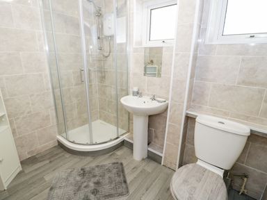 A bathroom with a shower enclosure sink toilet and a gray floor mat at 17 Ffordd Gwenllian in Llanfairpwllgwyngyll