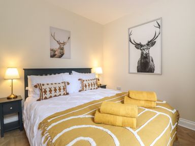 A bedroom with bed lamps pillows and yellow towels on the bed at Pond Cottage in Alnmouth