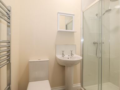 A bathroom with a toilet sink mirror cabinet towel radiator and glass shower enclosure
