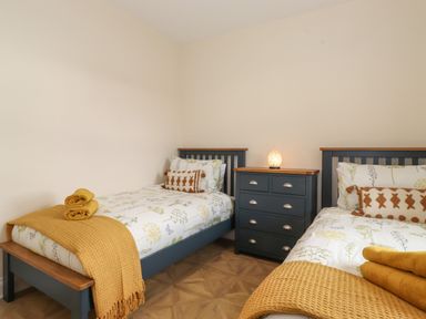 A bedroom with two single beds and a chest of drawers between them at Pond Cottage in Alnmouth