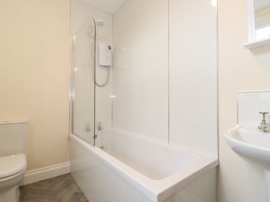A bathroom with a bathtub shower combination toilet and a sink at Pond Cottage in Alnmouth
