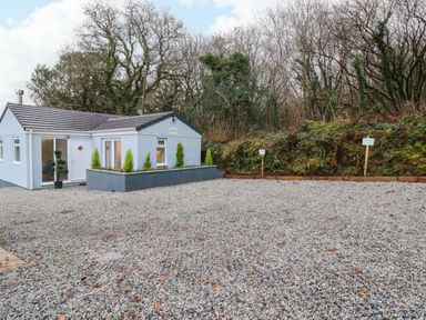 A gravel driveway leading to a small single-story building surrounded by trees at The View in Cardinham