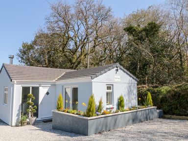 A small house with a tiled roof and flower beds in front at The View in Cardinham